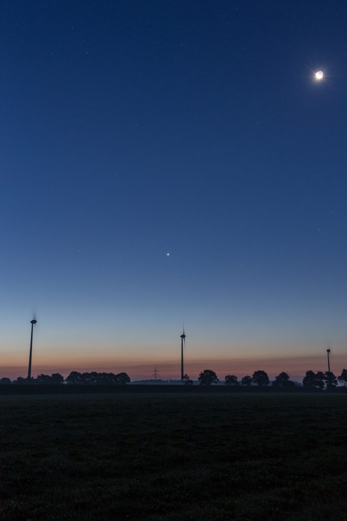 Von oben rechts nach unten links: Mond mit Erdschein, Venus, Merkur und Mars um 5:51 Uhr MESZ. Die letzten beiden stehen direkt am Horizont mittig zwischen den beiden Windrädern. (Bild: B. Knispel)